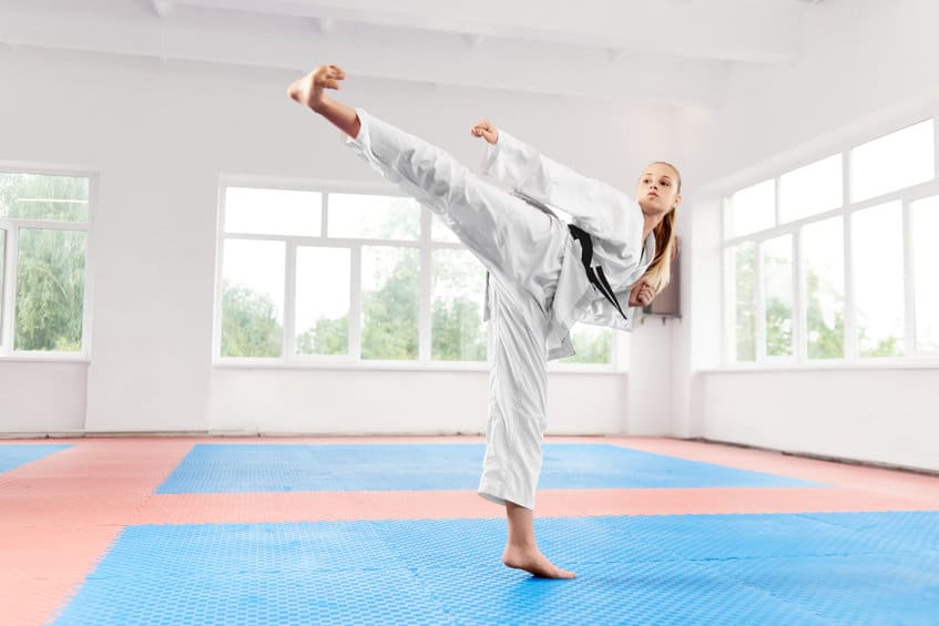 woman performing martial arts high kick at fight class.